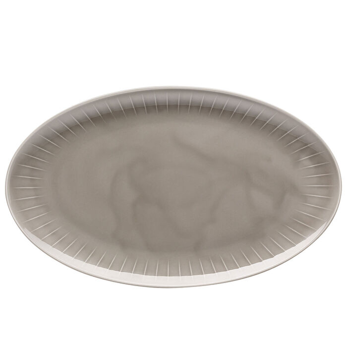 Ovalt serveringsfad i gråt porcelæn set oppefra, med fine riller langs kanten og hvid underside, på hvid bund
