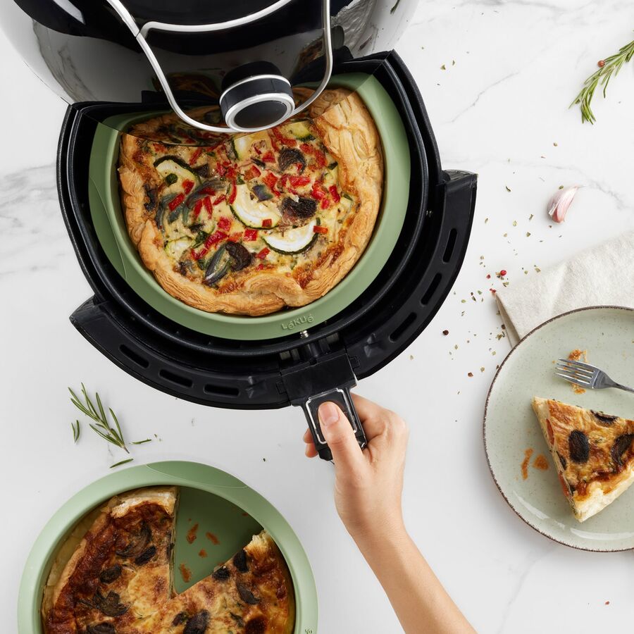 Airfryer med kurven trukket ud og en grøn silikoneindsats med en tærte i