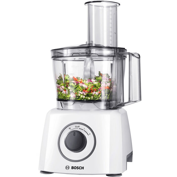 Hvid foodprocessor med stor sort drejeknap og Bosch-navn, klar skål med hakkede grøntsager og et højt påfyldningsrør, på hvid bund