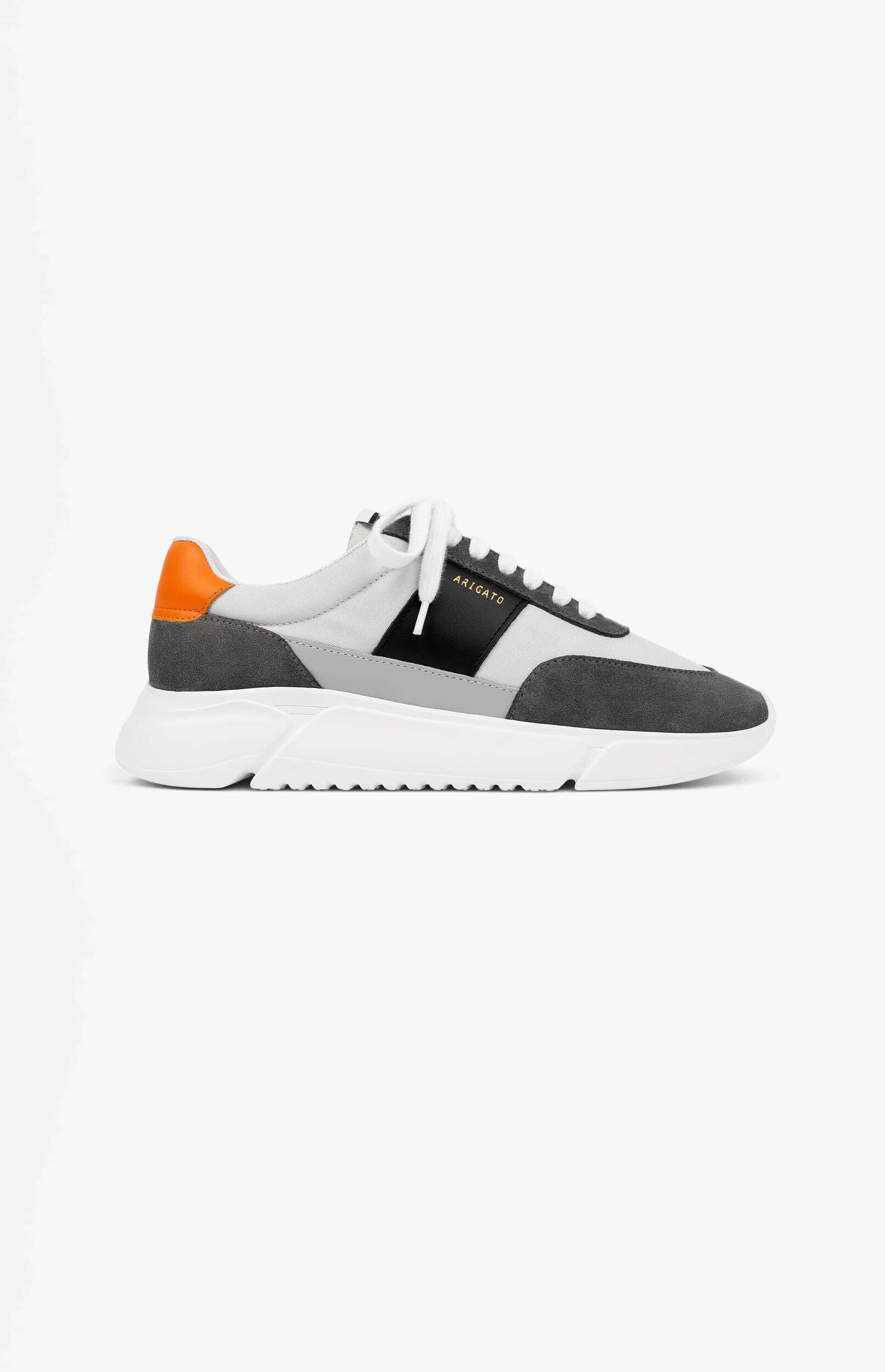 A grey and black Axel Arigato sneaker with an orange heel tab, white laces, and a thick white sole, presented on a clean white background.