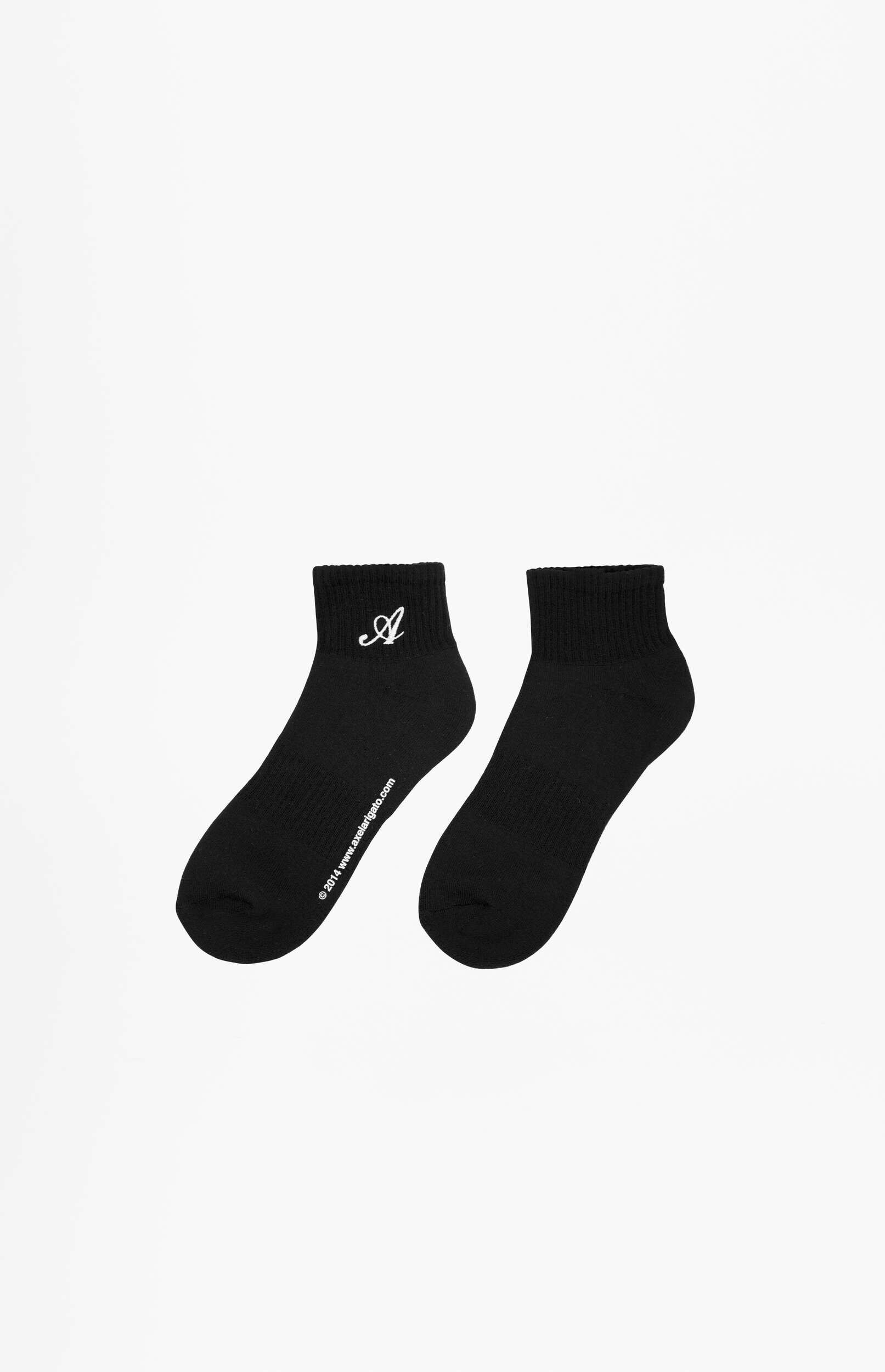 A pair of black ankle socks on a white background. The left sock features a white embroidered cursive 'A' near the cuff and '© 2014 www.axelarigato.com' printed along its side.