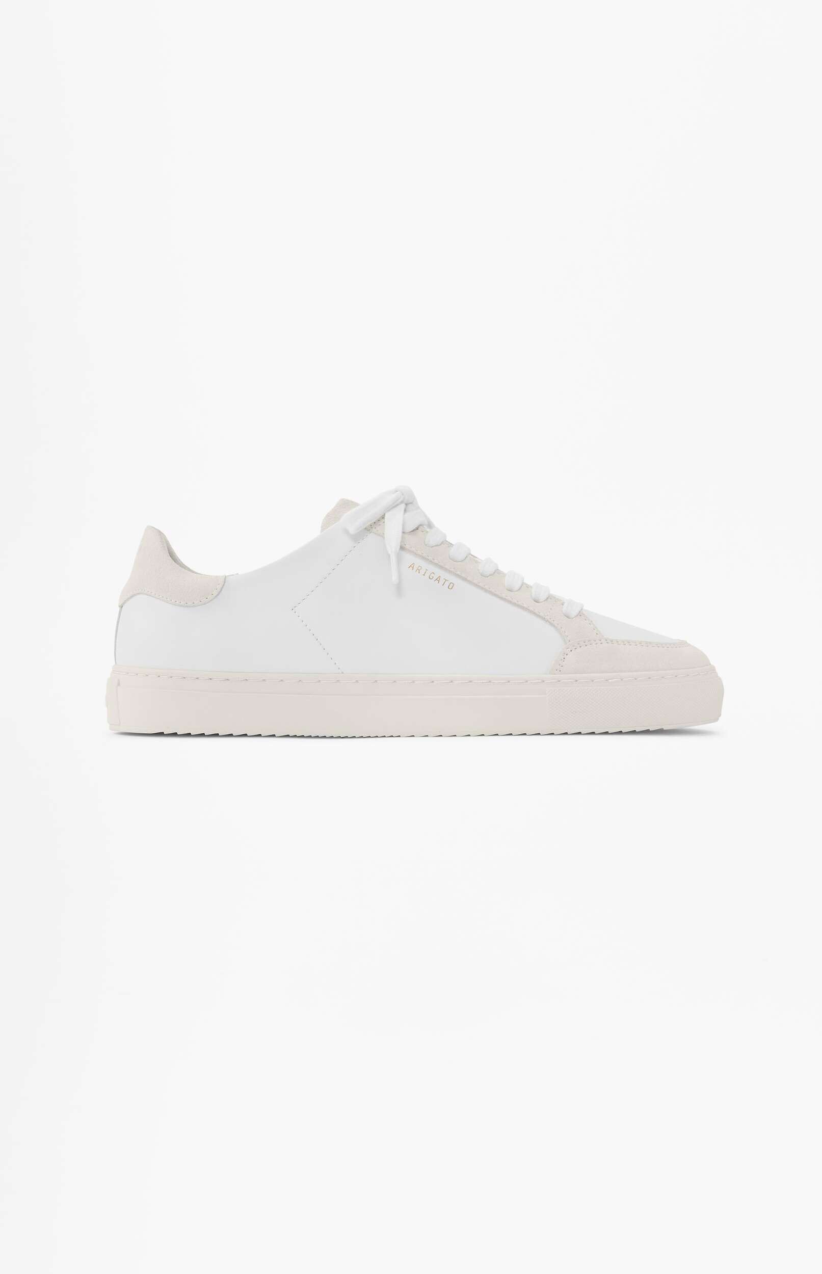 A minimalist white leather ARIGATO low-top sneaker with subtle light beige suede accents on the heel tab, eyelet strip, and sole, featuring gold 'ARIGATO' lettering on the side, presented on a clean white background.