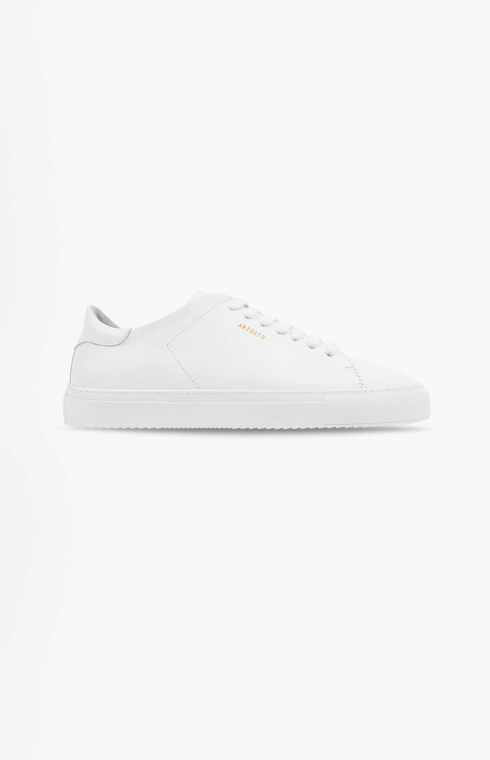 A minimalist white leather sneaker, featuring white laces and a clean white sole, against a plain white background. The brand name 'ARIGATO' is subtly visible in gold lettering on the shoe's side.