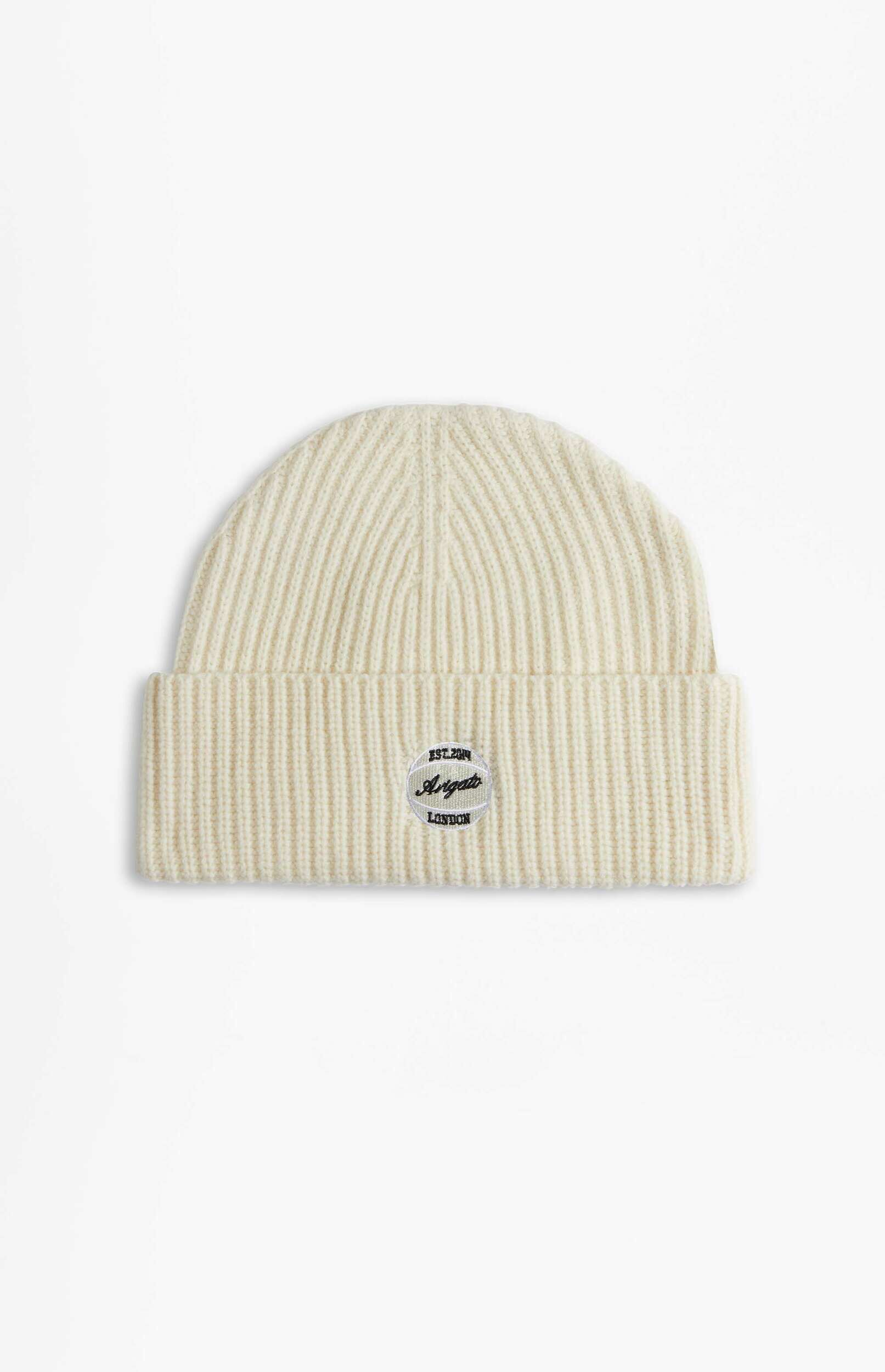 A cream-colored ribbed knit beanie with a circular patch on the folded brim that reads 'EST. 2014 Arigato LONDON' in black text.