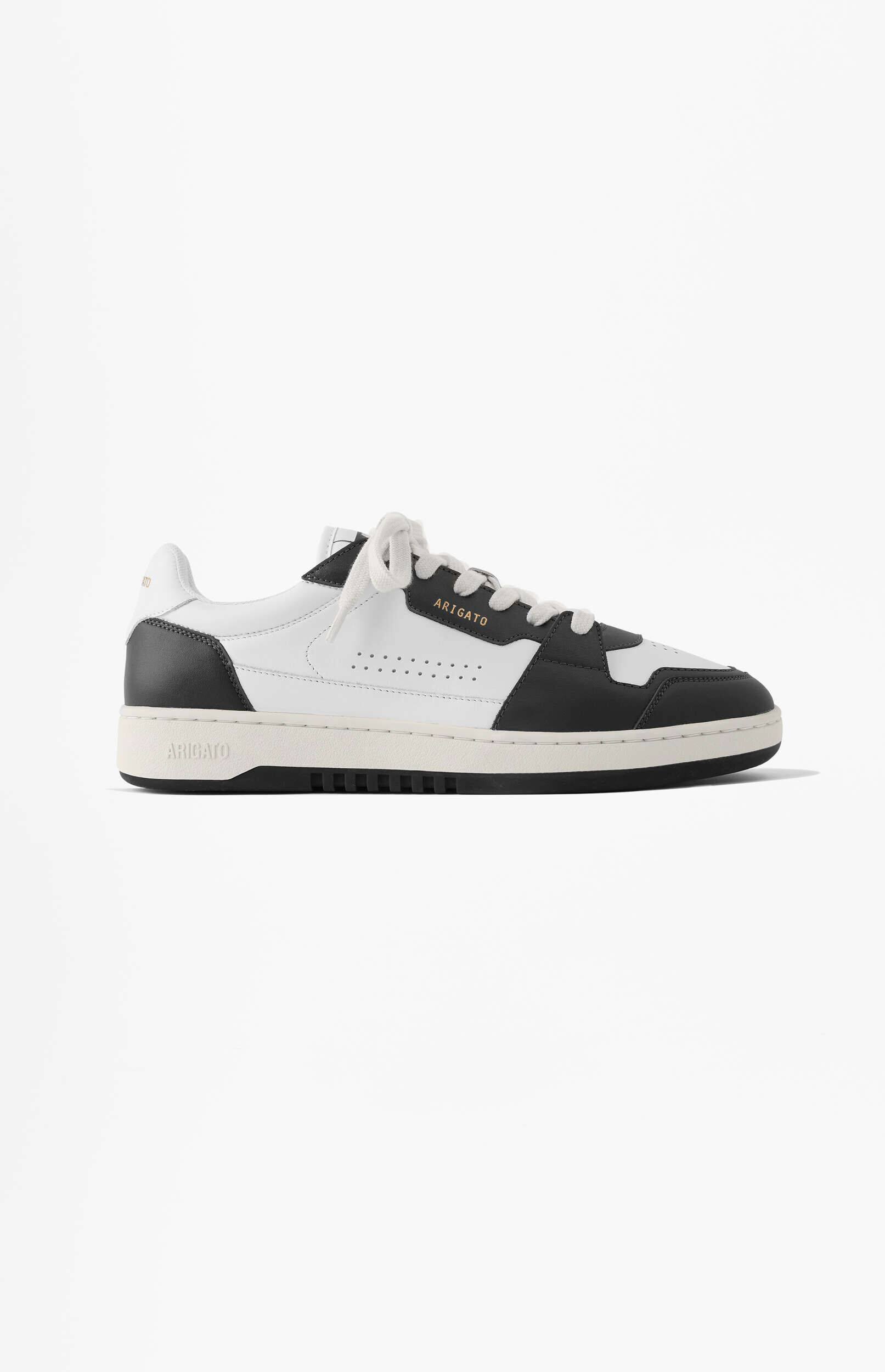 A side view of an Axel Arigato Dice Lo sneaker, featuring a clean white leather upper with dark grey panels and a cream-colored sole, set against a plain white background.