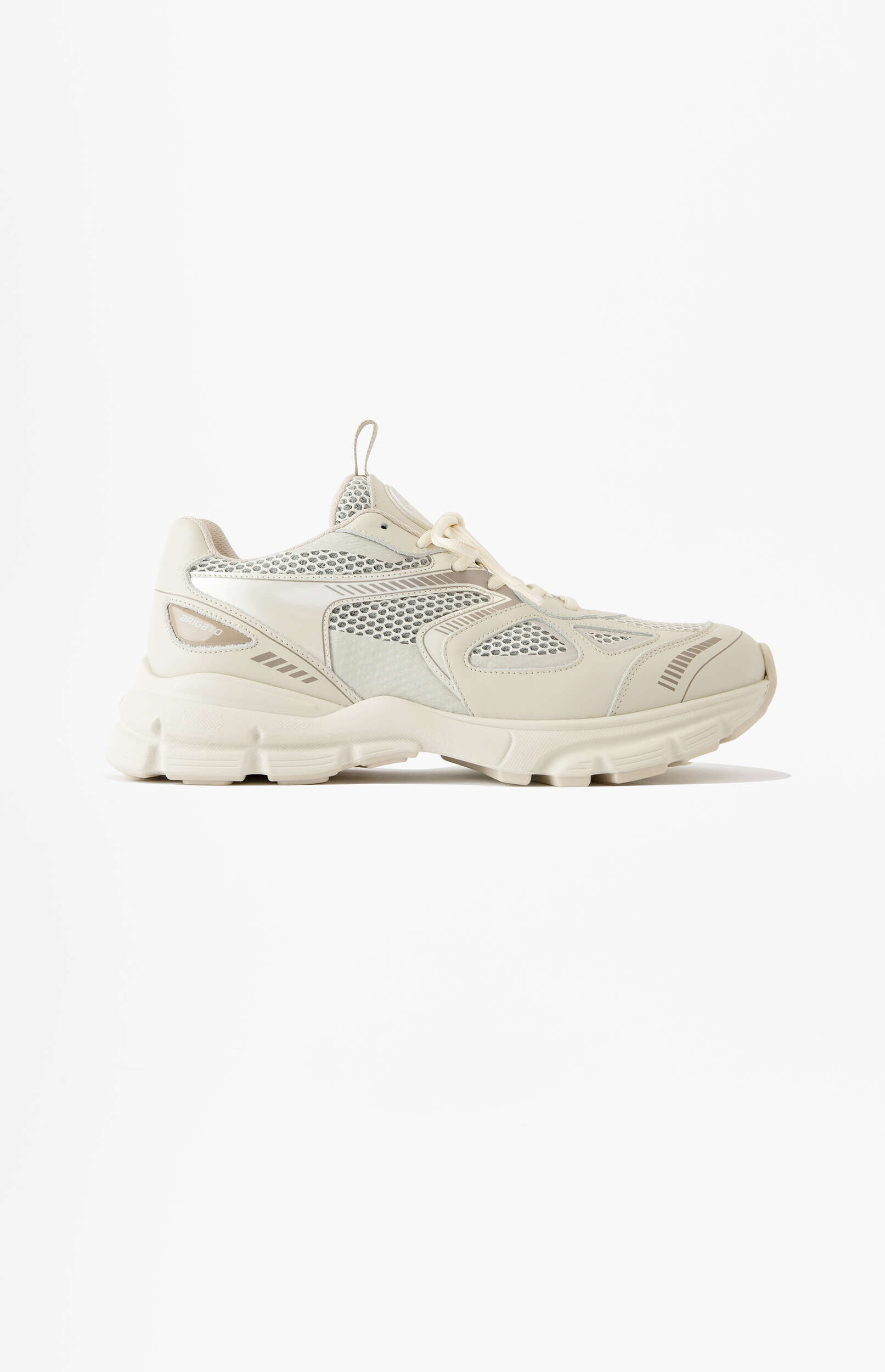 A single cream-colored athletic sneaker with a thick sole and a mix of mesh and synthetic overlays, displayed from the side on a white background.