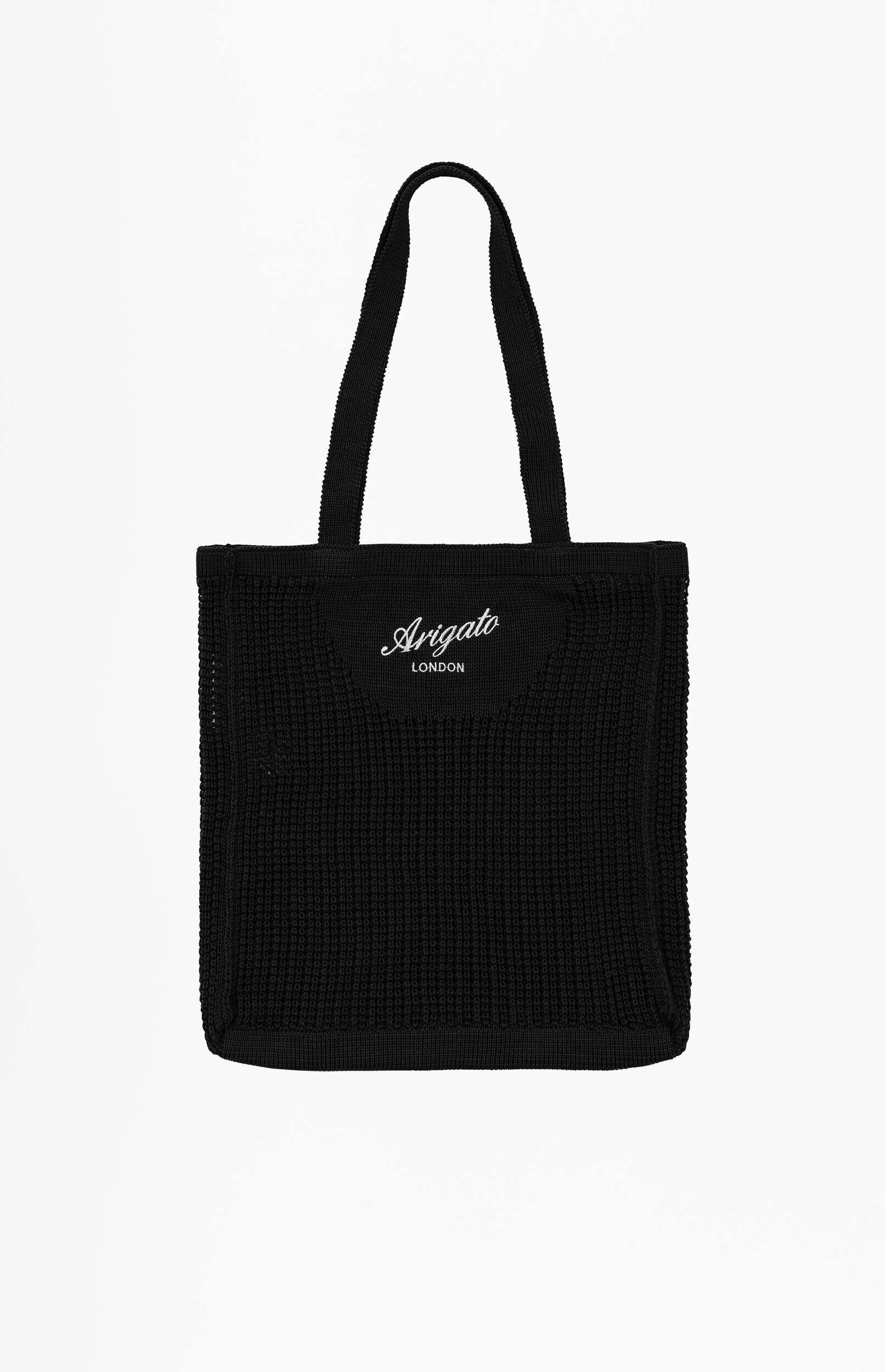 A black knitted tote bag featuring the white embroidered 'Arigato London' logo centered on the front, with two black fabric handles, set against a plain white background.