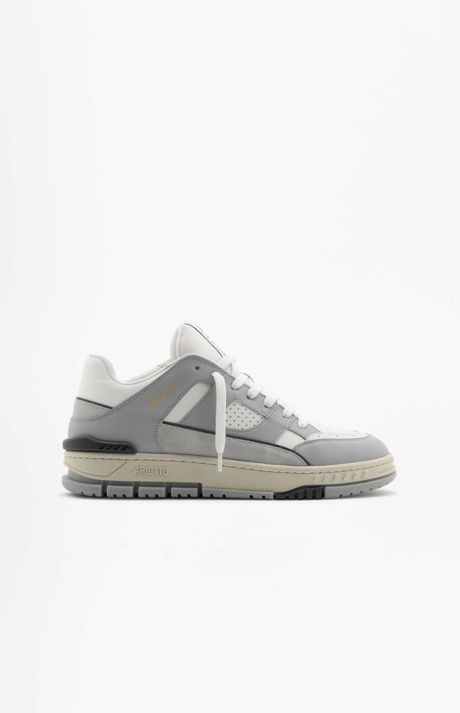 A single light grey, white, and beige Axel Arigato platform sneaker, viewed from the side against a clean white background. The athletic shoe features a layered upper with white laces, subtle perforations on the side panel, and a prominent chunky sole. The brand name 'ARIGATO' is visible in black on the beige midsole.
