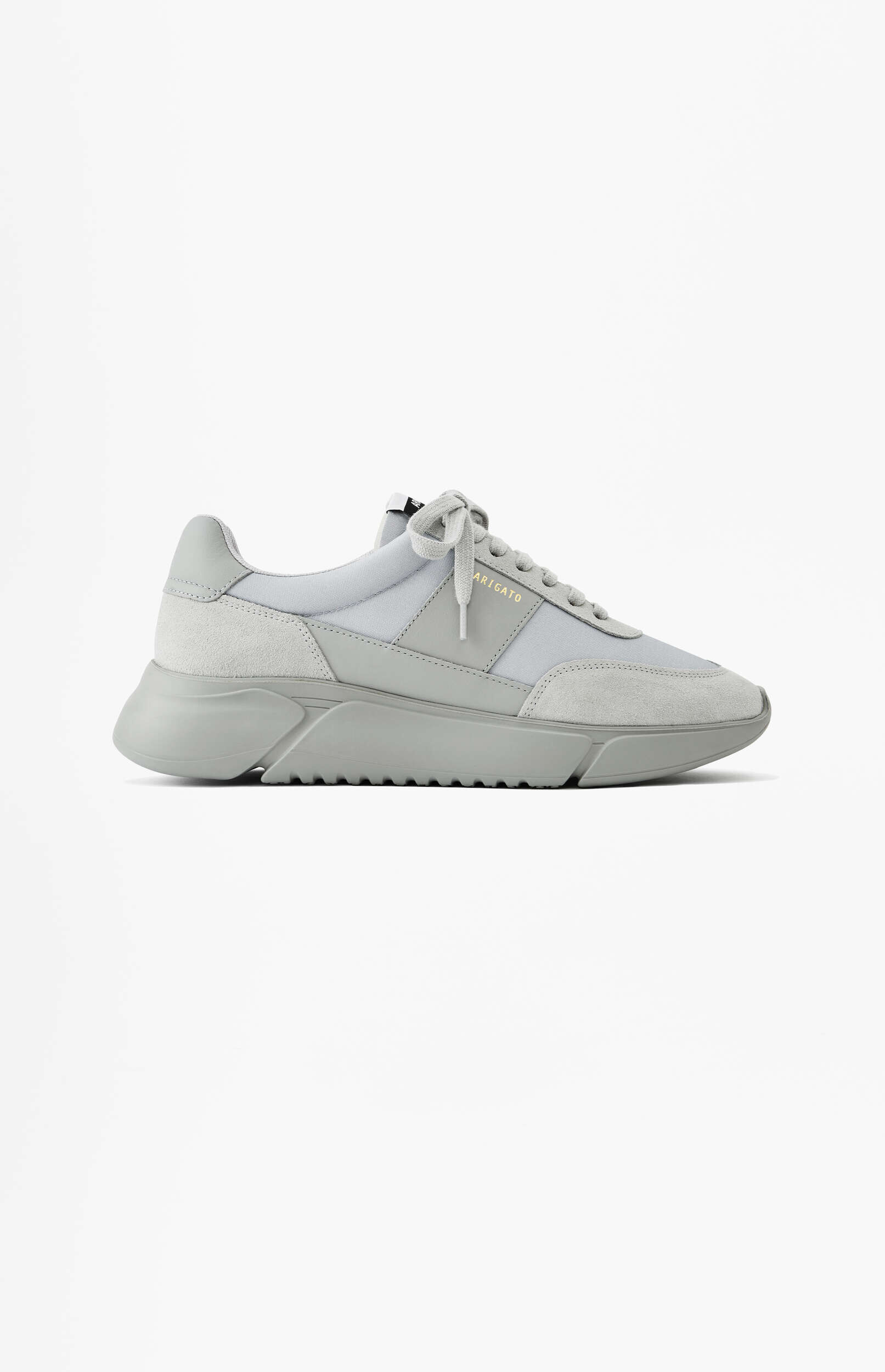 A light grey Axel Arigato sneaker with a thick, sculpted sole and textured upper, featuring suede and textile panels. The gold 'ARIGATO' brand name is visible on the side, and the shoe is displayed facing left on a plain white background.