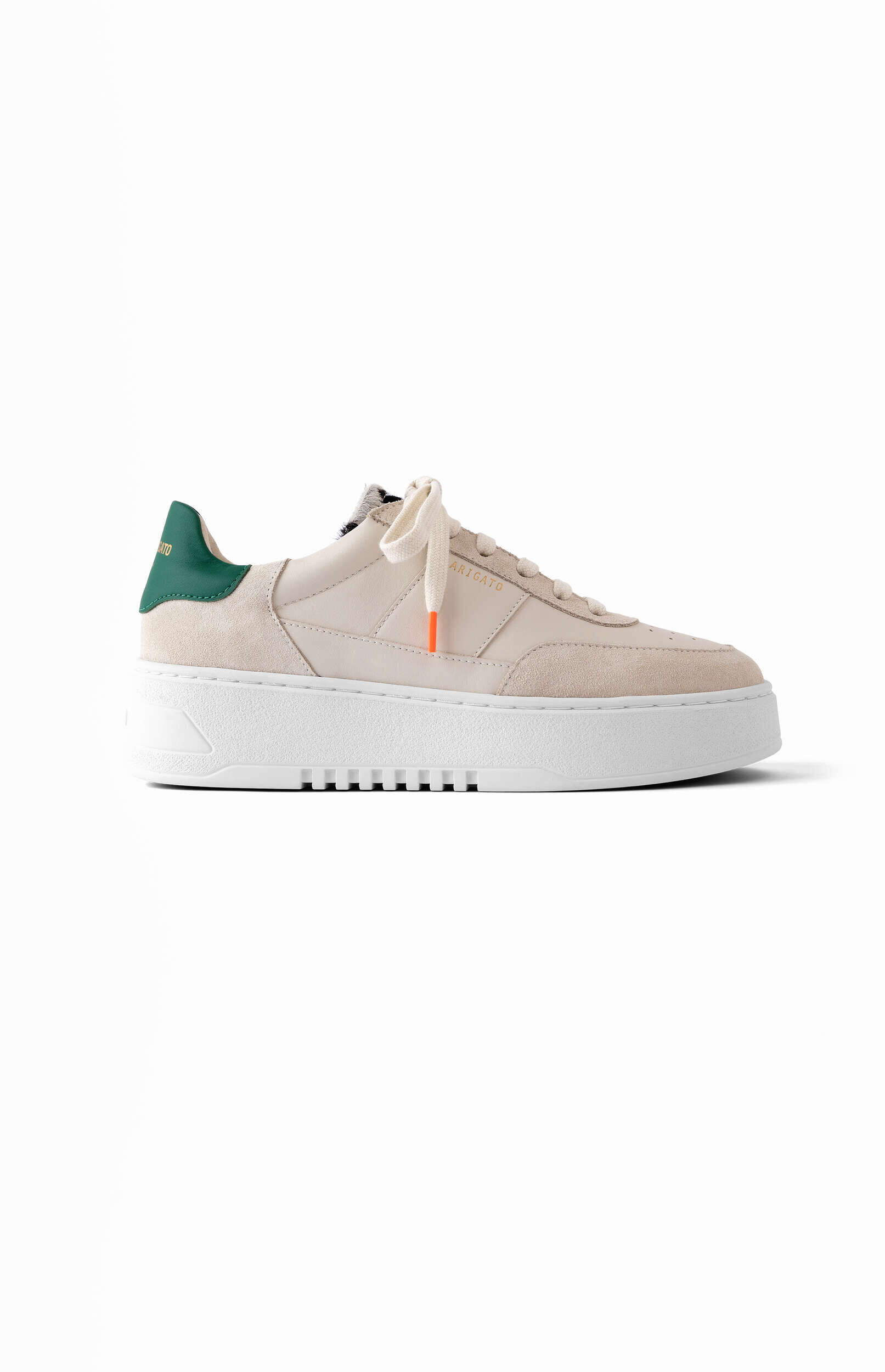 A light beige, cream-colored sneaker with a thick white platform sole and white laces. The shoe features a dark green heel tab and a small orange accent on one of the shoelace aglets. The brand name 'ARIGATO' is subtly visible on the side of the shoe. The sneaker is shown from a side profile on a clean white background.