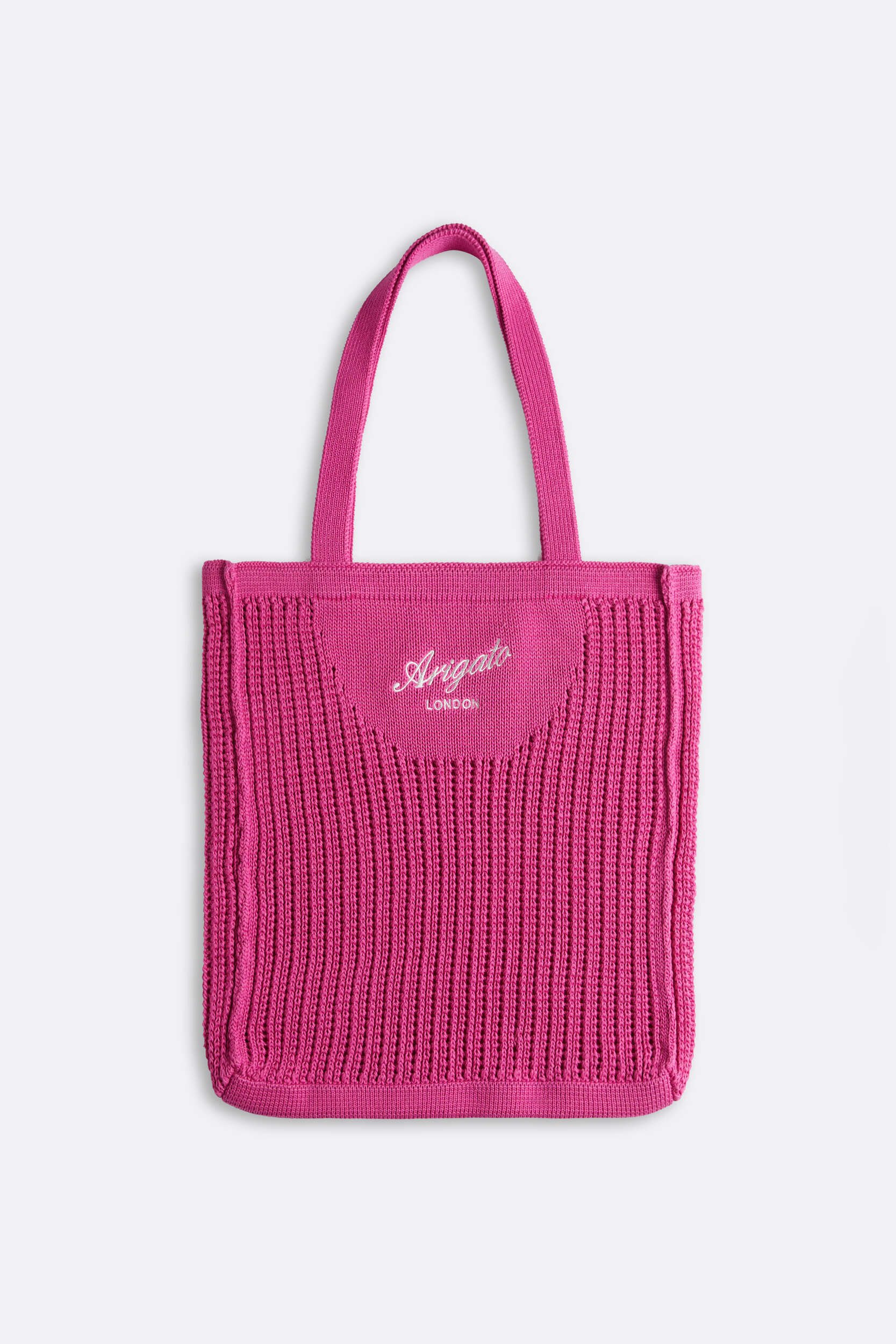 A vibrant fuchsia pink knitted tote bag with two top handles. The front features 'Arigato' in white cursive script with 'LONDON' written below it.