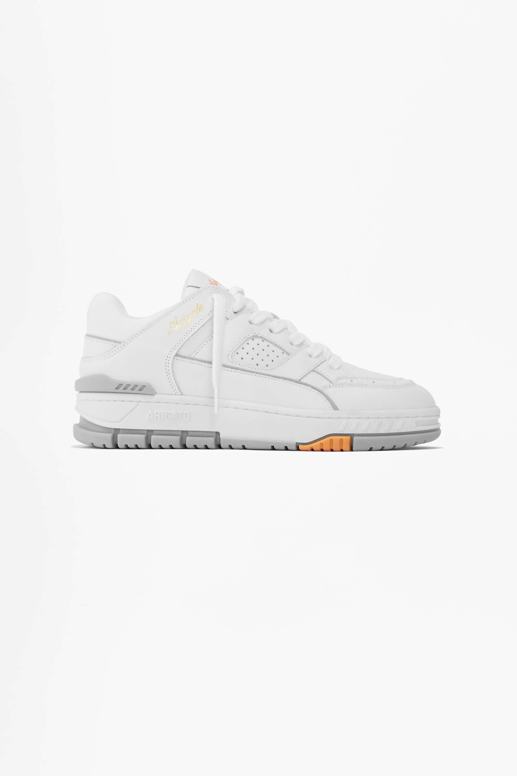 A white low-top sneaker with light grey sole accents and a subtle orange detail near the toe, featuring 'ARIGATO' embossed on the side of the sole and 'Angelo' written in cursive on the upper.