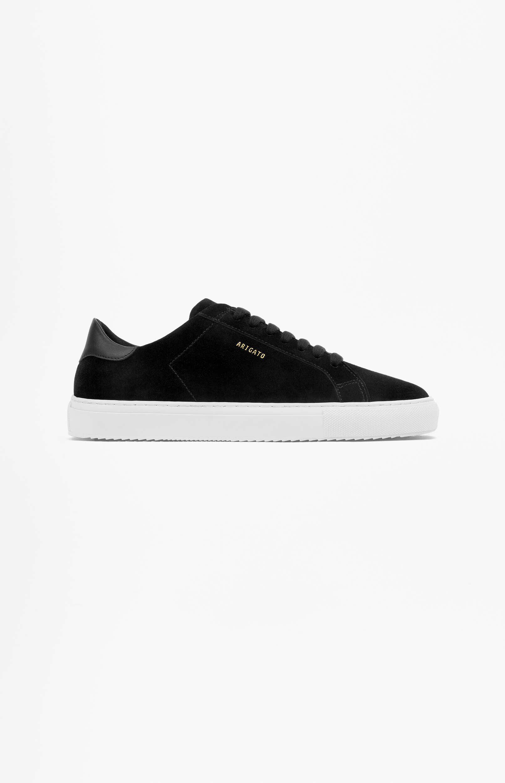 A side view of a black suede Axel Arigato Clean 90 sneaker with a white rubber sole, featuring 'ARIGATO' in gold text on the side, set against a plain white background.
