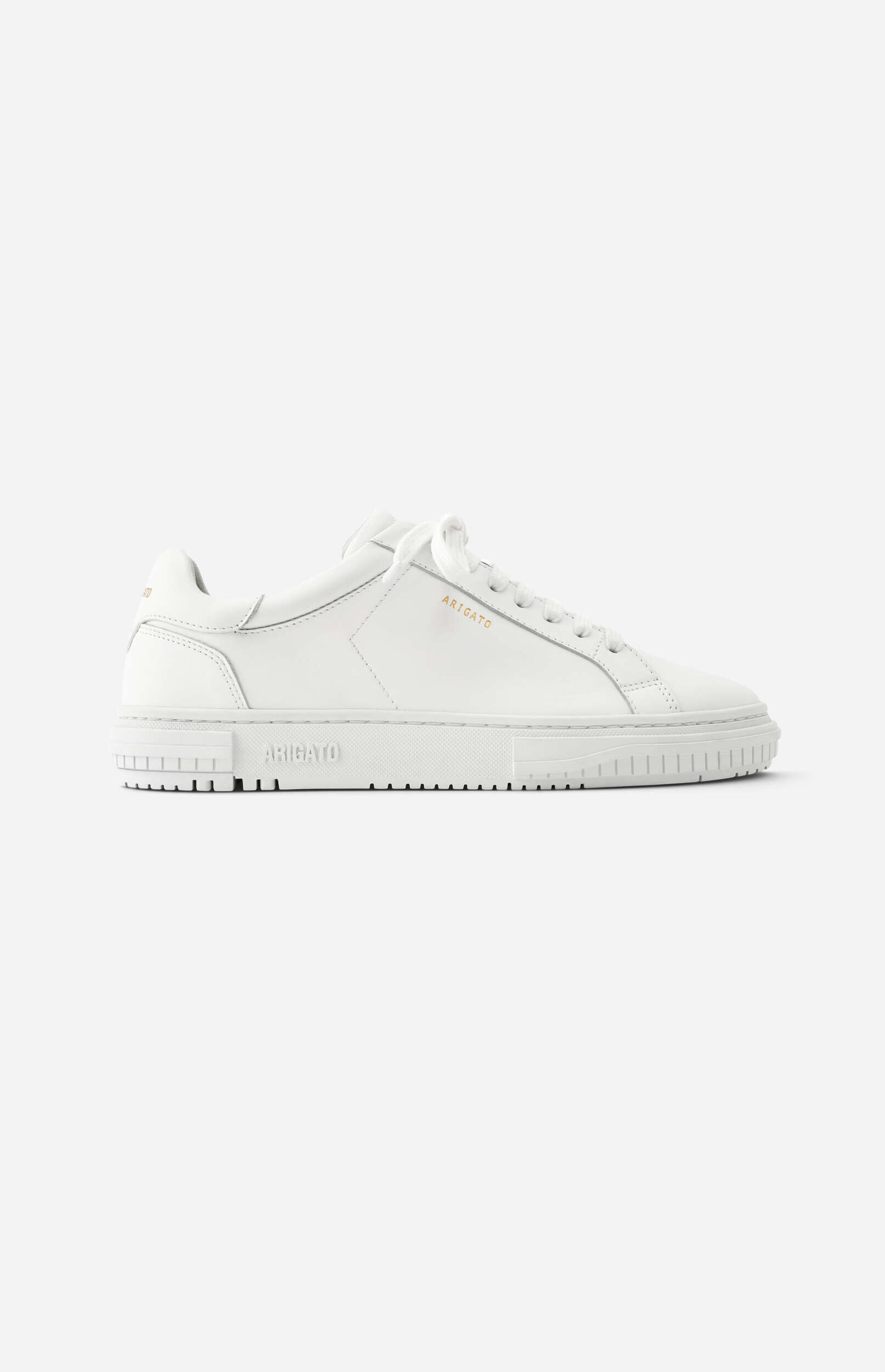 A clean, white leather low-top sneaker by ARIGATO, with matching white laces and a white sole, featuring gold embossed 'ARIGATO' lettering on the side, viewed against a plain white background.