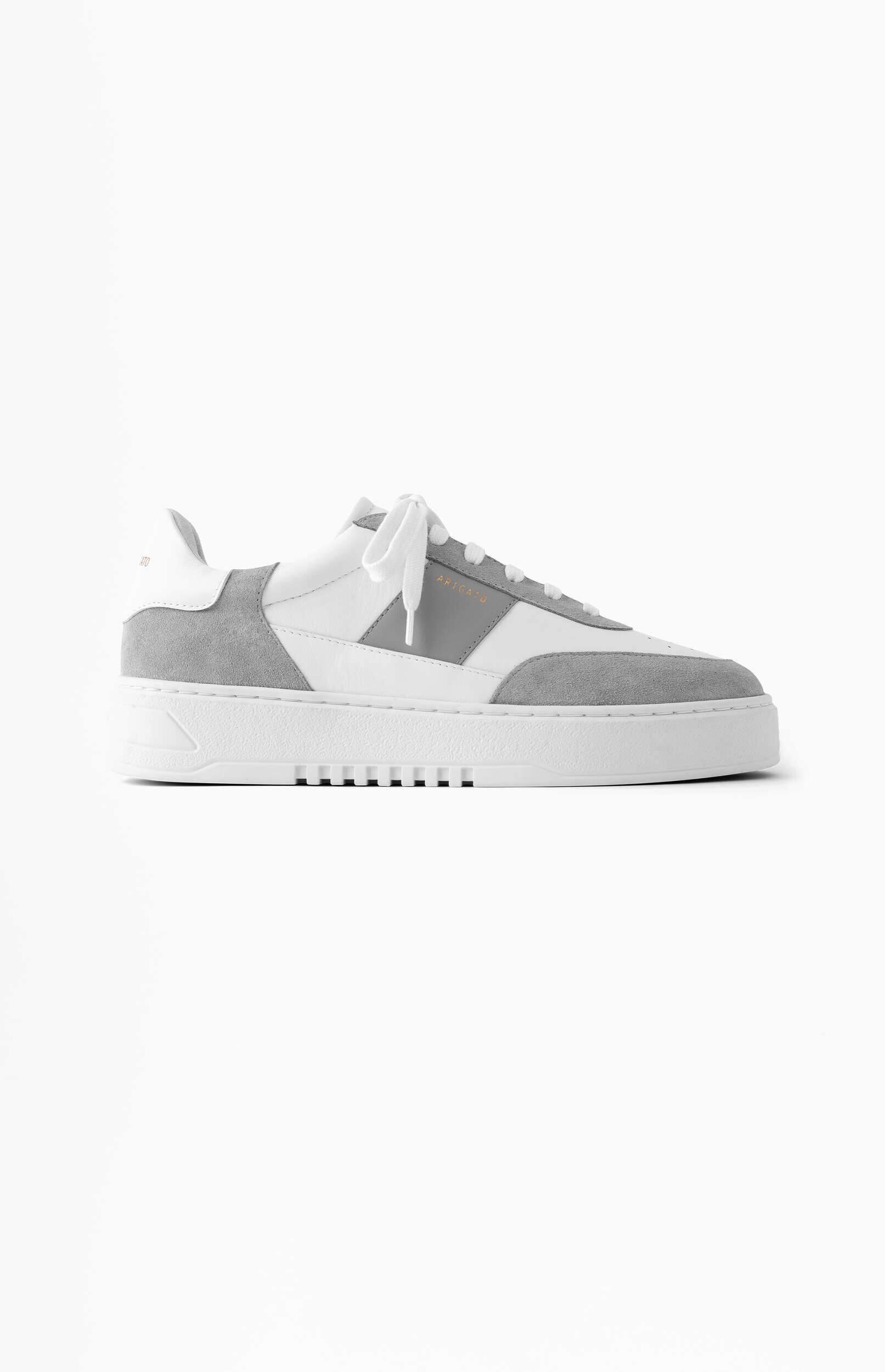 A white and light grey sneaker with a thick white sole, viewed from the side on a plain white background. The shoe features white leather sections, light grey suede accents, and white laces. The brand name 'ARIGATO' is visible on the side panel.