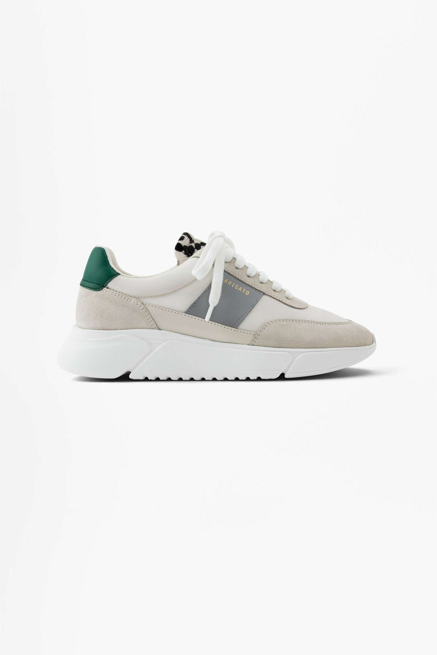 A cream and light grey Axel Arigato sneaker with a dark green heel tab, white laces, and a chunky white sole, displayed from the side on a plain white background.