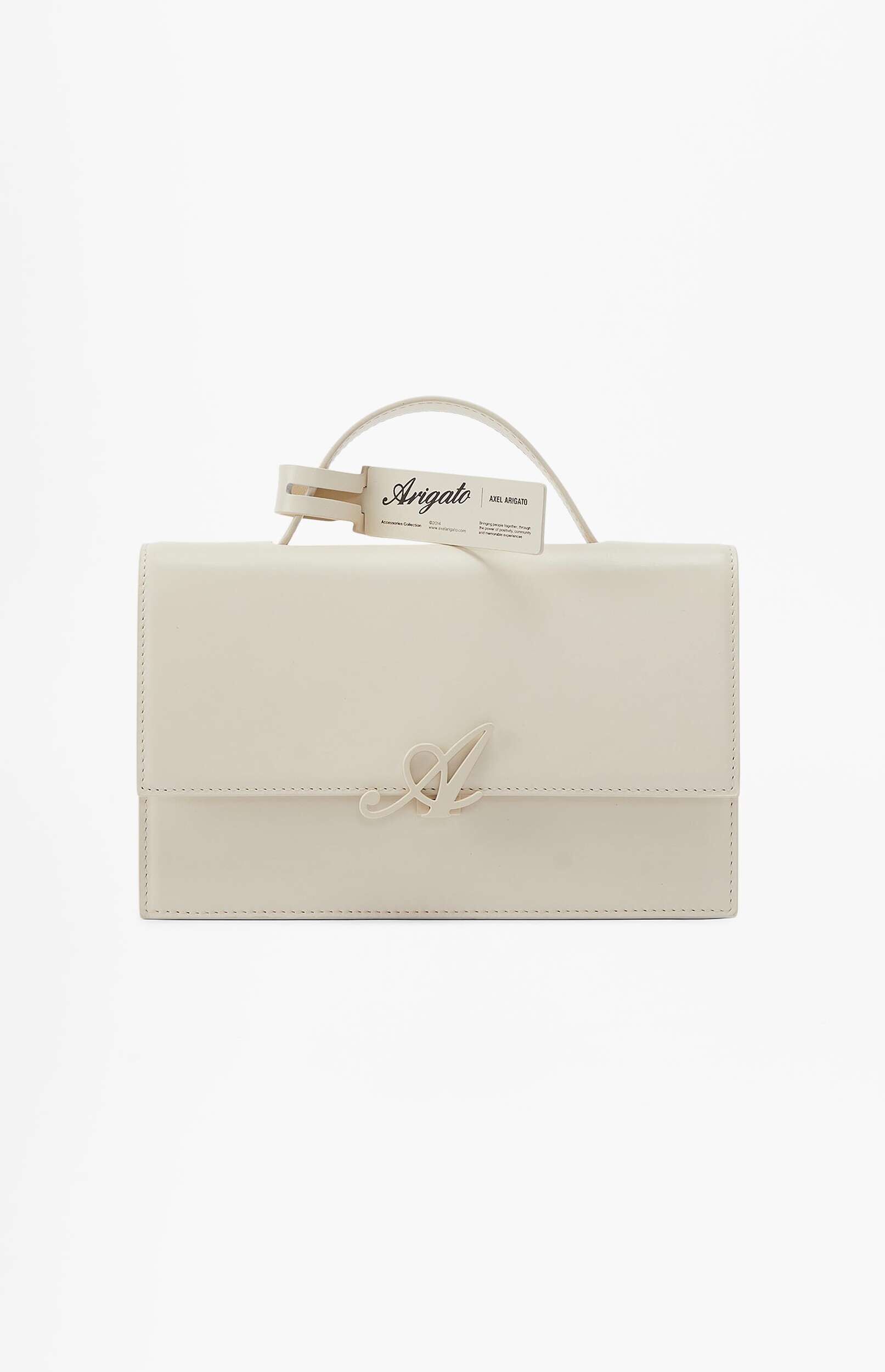 Cream-colored leather handbag with a flap closure, featuring a prominent gold-toned 'A' logo on the front and an attached 'Arigato Axel Arigato' brand tag on the handle, against a white background.