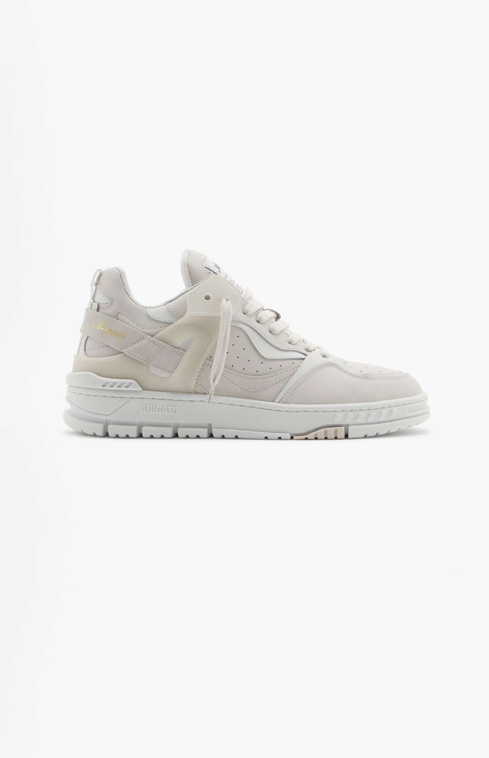 A light grey and off-white Axel Arigato Genesis Vintage Runner sneaker is shown from a side profile, with a chunky textured sole. The sneaker features mixed materials including leather and suede, with 'ARIGATO' visible on the midsole and 'Axel Arigato' embroidered on a strap near the ankle. The background is solid white.