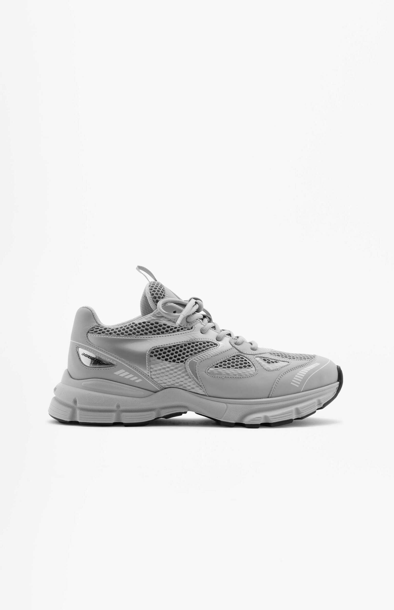 A side view of a single light gray athletic sneaker featuring a thick sole, mesh upper, and synthetic overlays, set against a plain white background.