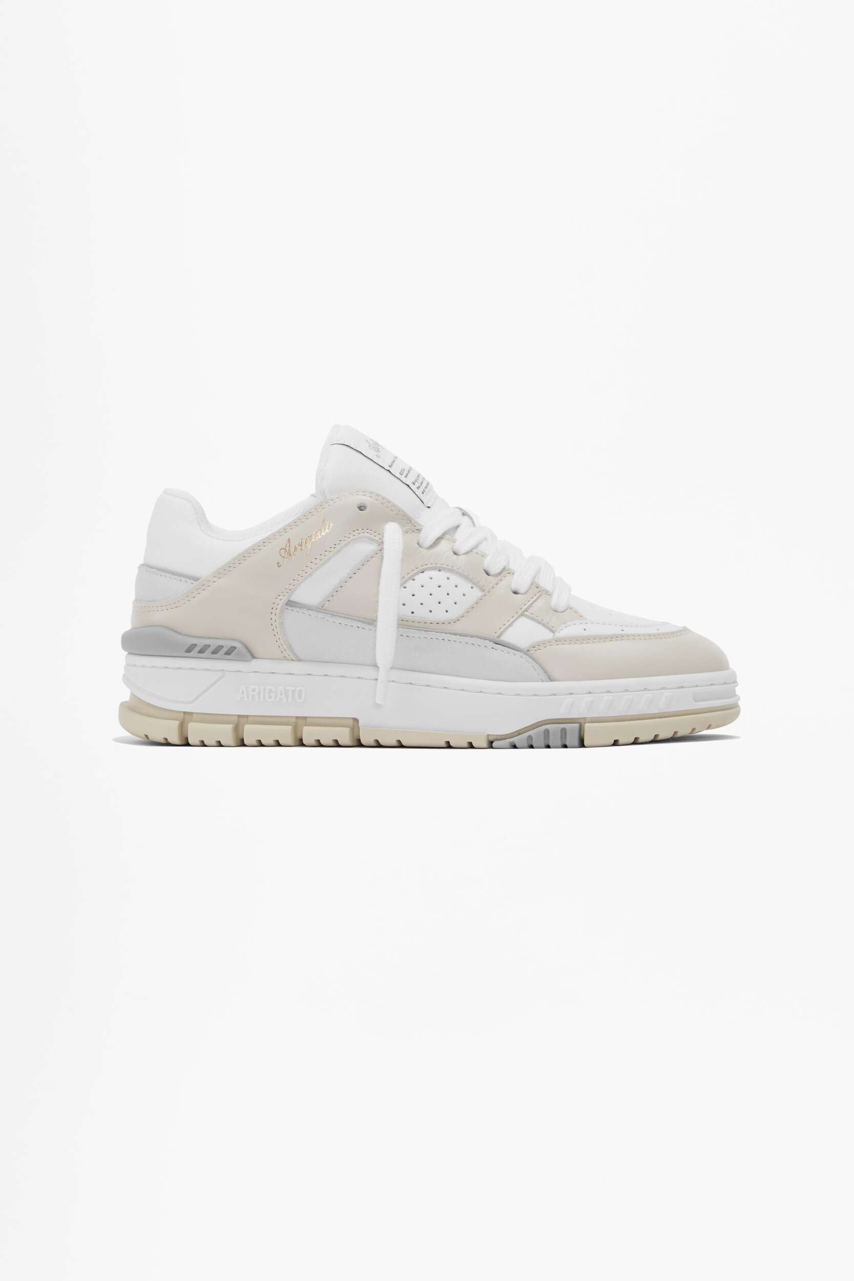 A white and beige Axel Arigato sneaker with a chunky sole, viewed from the side on a plain white background. The shoe features white laces, perforated details, and visible 'ARIGATO' branding on the midsole.