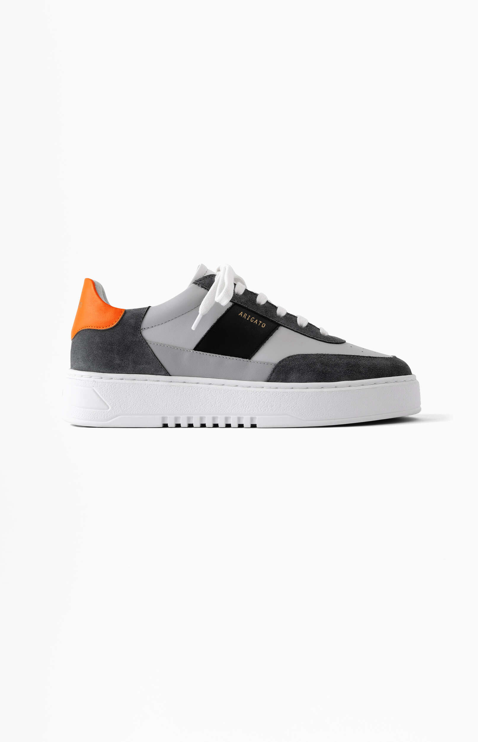 A stylish grey, dark grey, and black sneaker with white laces, a white sole, and a vibrant orange heel accent, featuring the 'ARIGATO' brand name on the side, displayed against a clean white background.