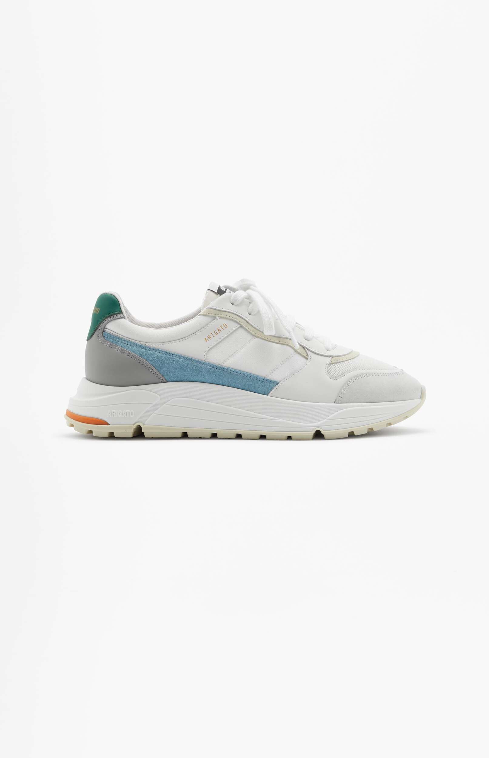 A side view of a white sneaker with light blue and grey accents, and a dark green heel tab. The shoe has white laces and an off-white sole with a small orange detail near the back. The brand name 'ARIGATO' is visible on the side. The sneaker is shown against a plain white background.