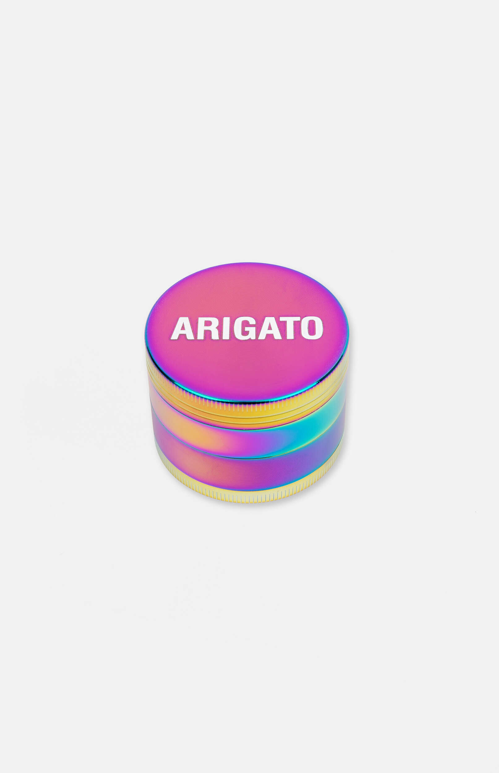 A cylindrical metal grinder with an iridescent finish, displaying colors like pink, purple, blue, green, and gold. The word "ARIGATO" is embossed in white on the top surface. The object is centered on a light grey background.