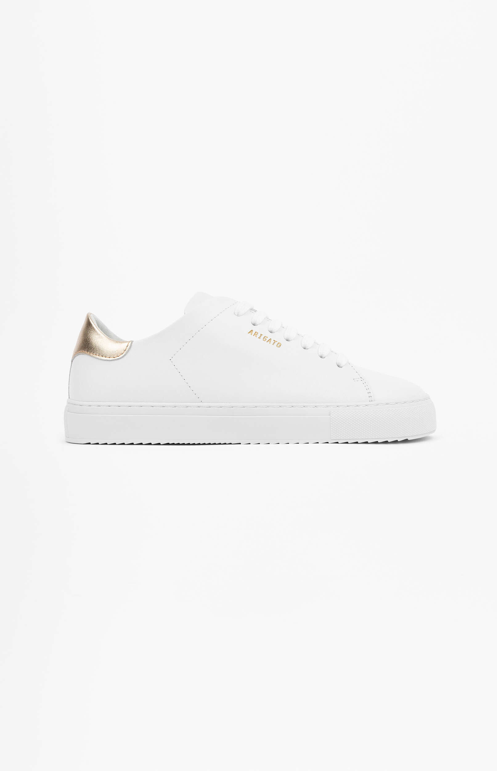 A white minimalist sneaker with a gold heel tab and a gold 'ARIGATO' logo on the side, presented on a clean white background.