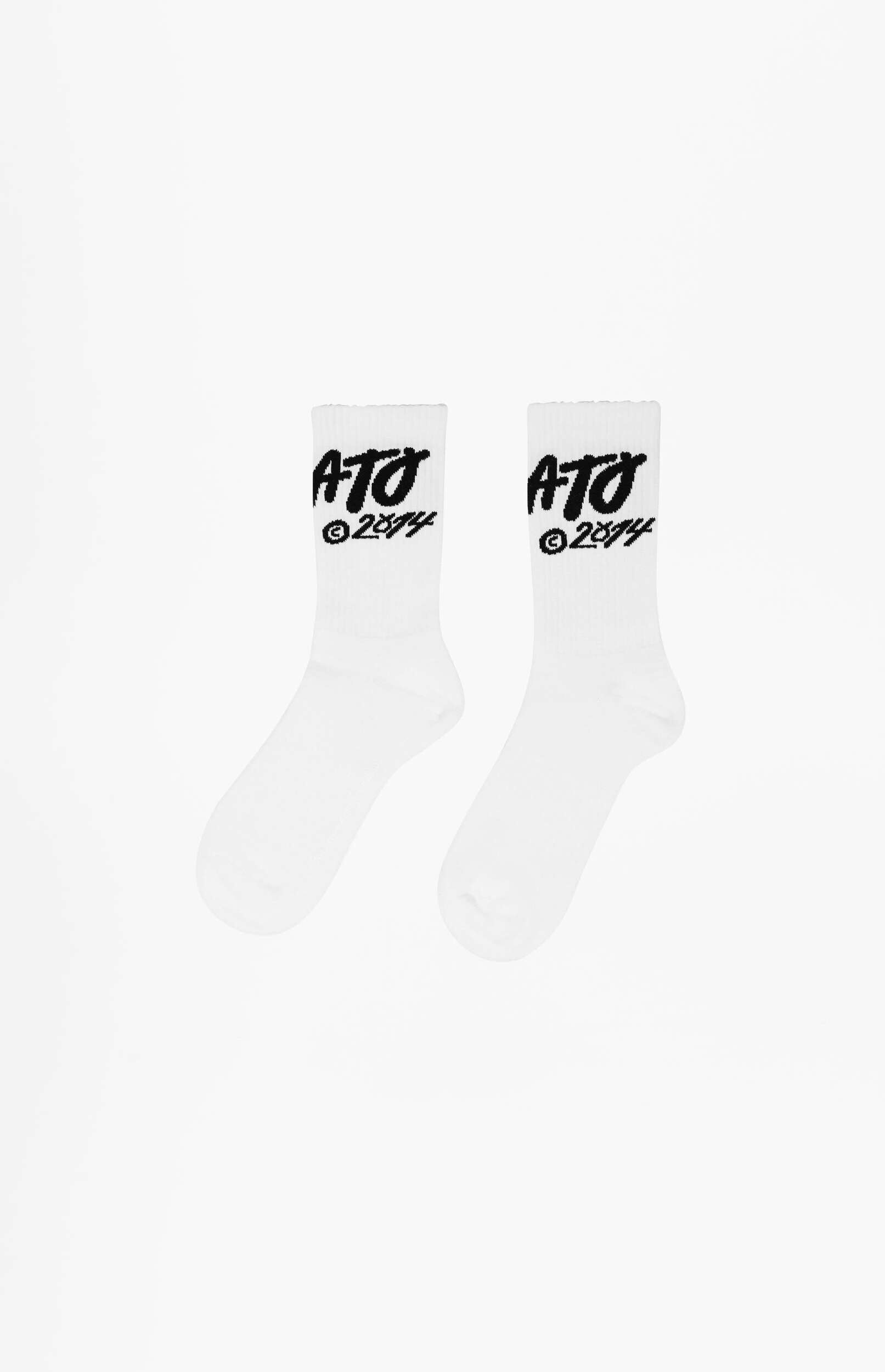 A pair of white crew socks with black 'ATO ©2024' branding prominently displayed on the upper ankle, set against a clean white background.