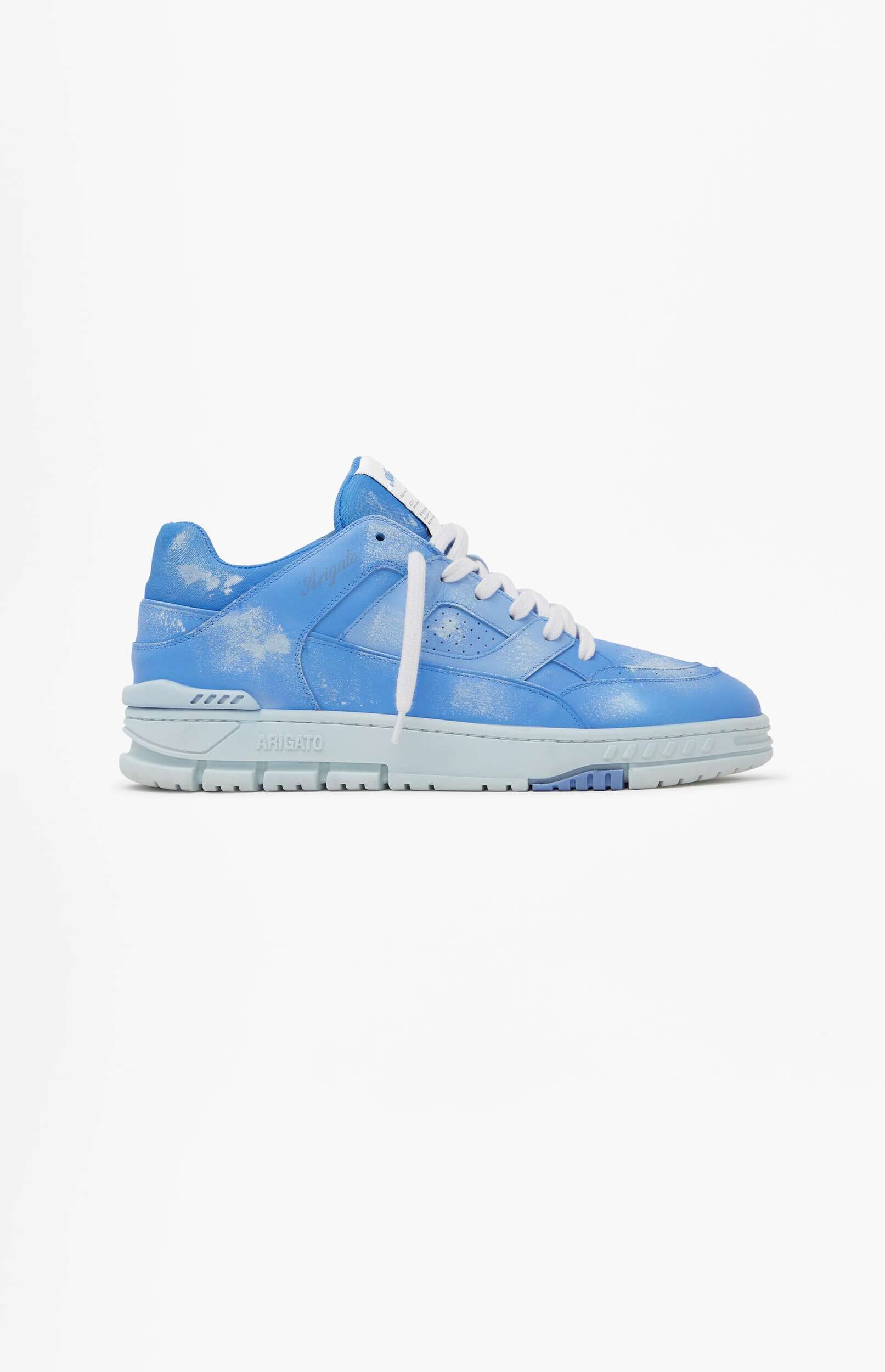 A light blue low-top sneaker with a white distressed or splatter effect, white laces, and 'ARIGATO' branding on the light blue sole, displayed on a white background.