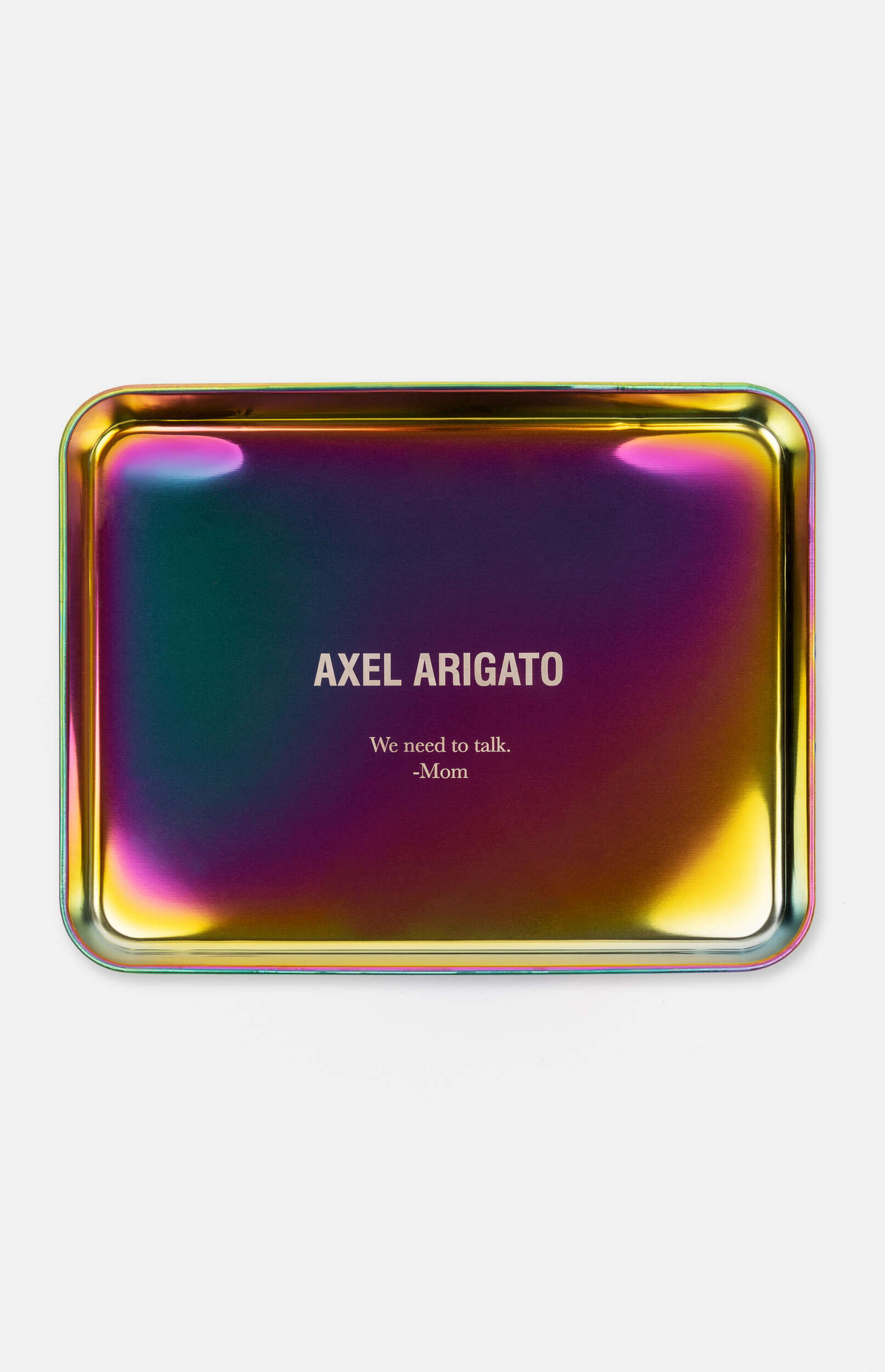 A rectangular, iridescent metal tray with rounded corners and raised edges, displaying a colorful, shimmering surface in shades of purple, green, yellow, and blue. White text is printed in the center, reading "AXEL ARIGATO" in a larger font, followed by "We need to talk." and "-Mom" in a smaller font below.