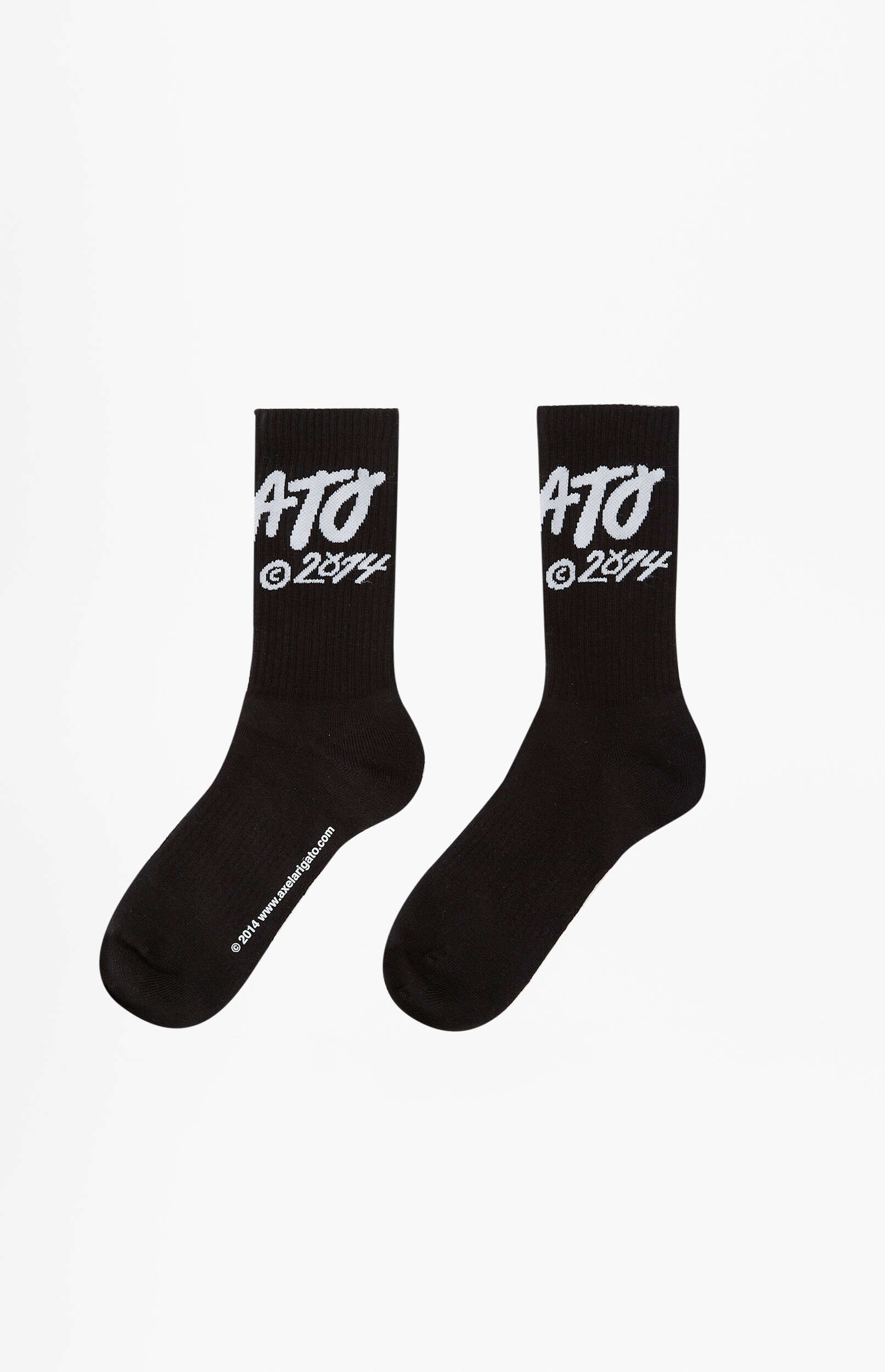 A pair of black crew socks with white text "ATO" and "©2014" on the upper part, displayed side by side on a white background. One sock also shows "www.axelartigato.com" along its foot.