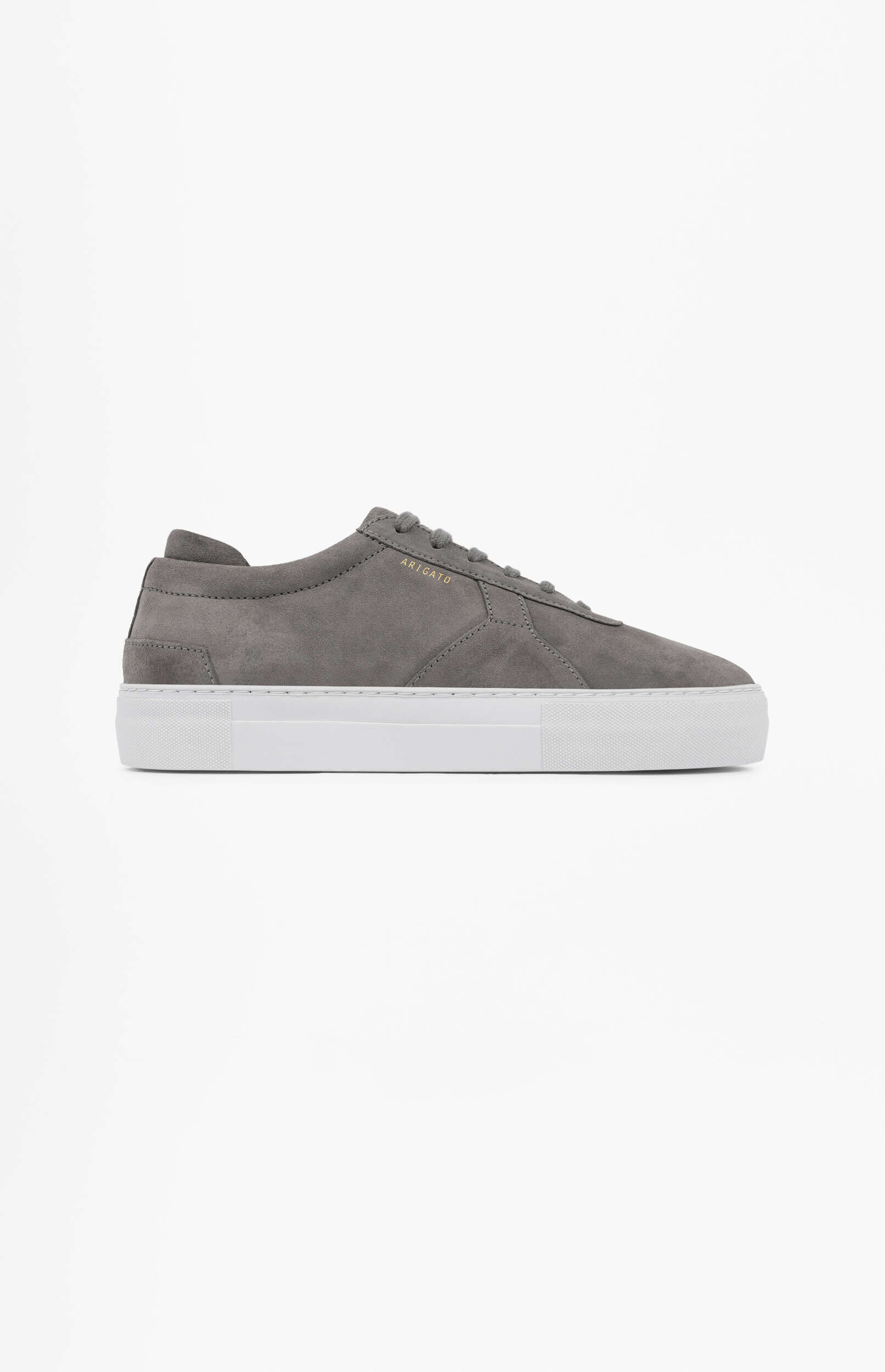 A minimalist grey suede sneaker with white laces and a thick white platform sole, featuring gold 'ARIGATO' branding on the side. The shoe is oriented to the right on a clean white background.