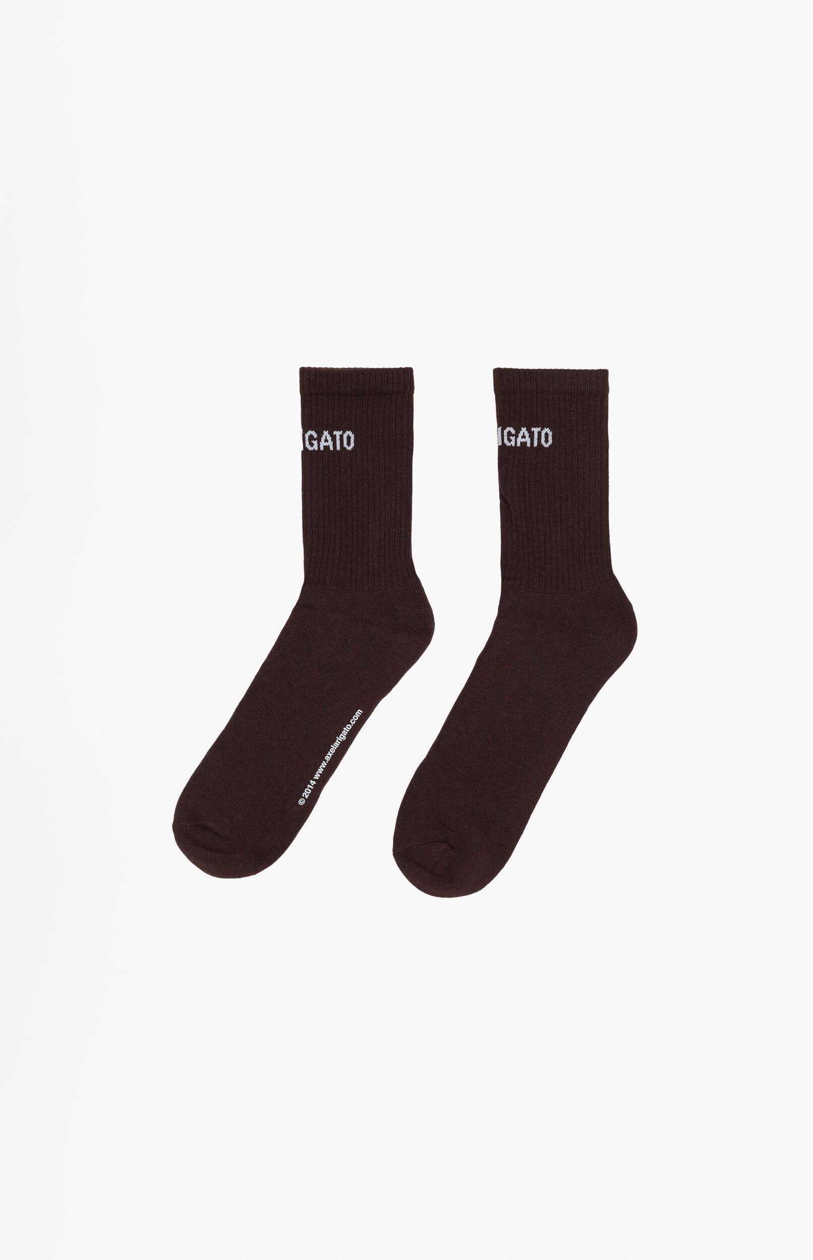 A pair of dark brown crew socks, displayed diagonally on a plain white background. Both socks feature 'IGATO' embroidered in white near the top cuff. The left sock also displays the text '© 2014 www.axelartigato.com' along the side of the foot.