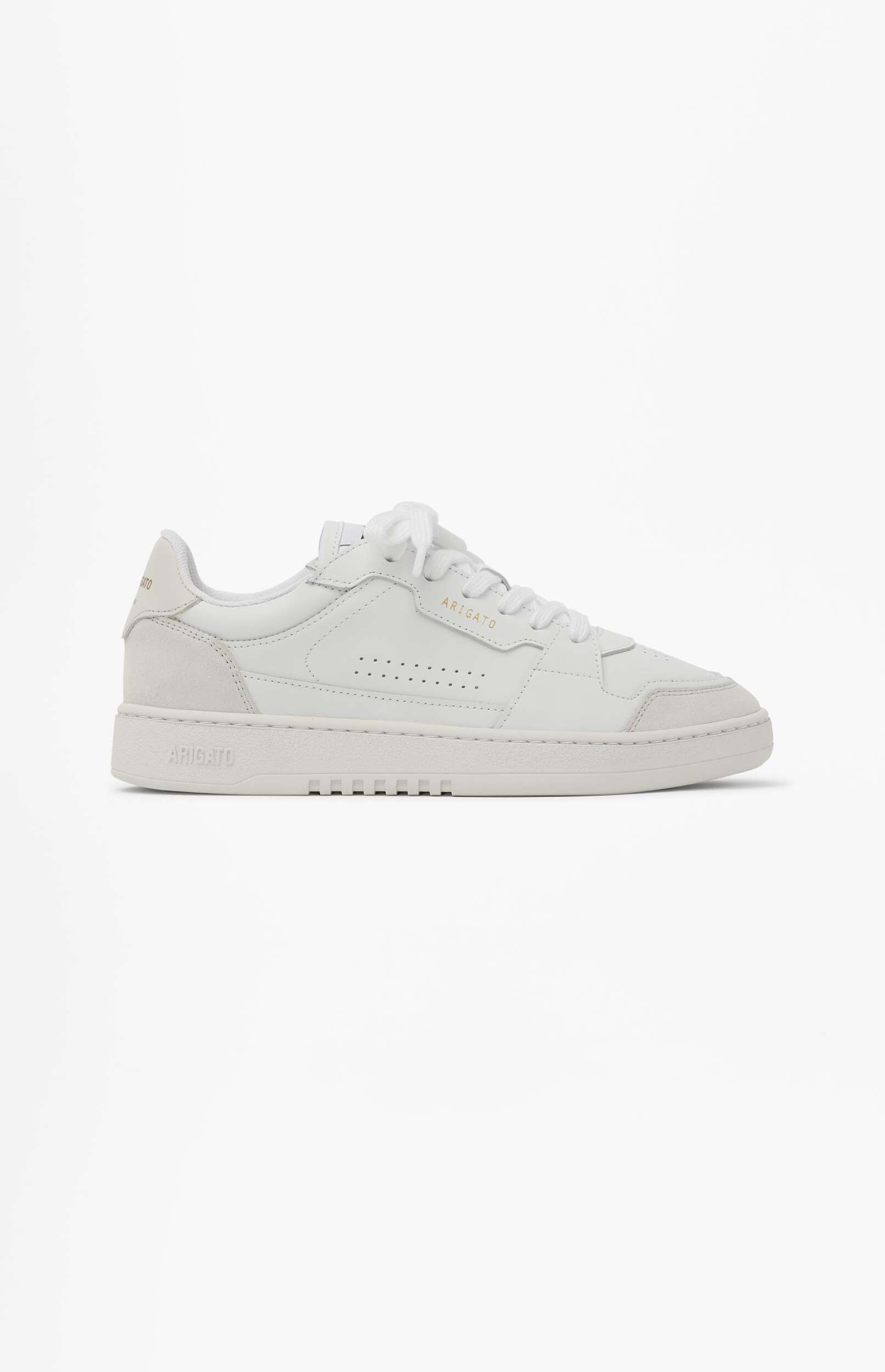 A white low-top sneaker with gold 'ARIGATO' branding on the side, featuring perforated details, light grey suede accents on the heel and toe, and white laces, presented on a clean white background.