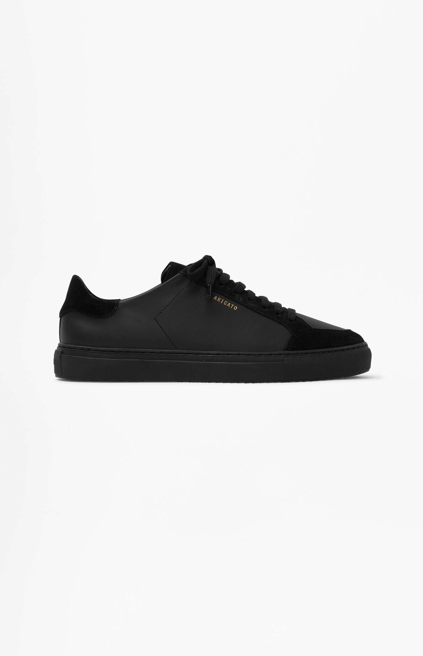 A single black low-top sneaker by Arigato, featuring smooth and suede textures, with a gold logo on the side, presented on a clean white background.