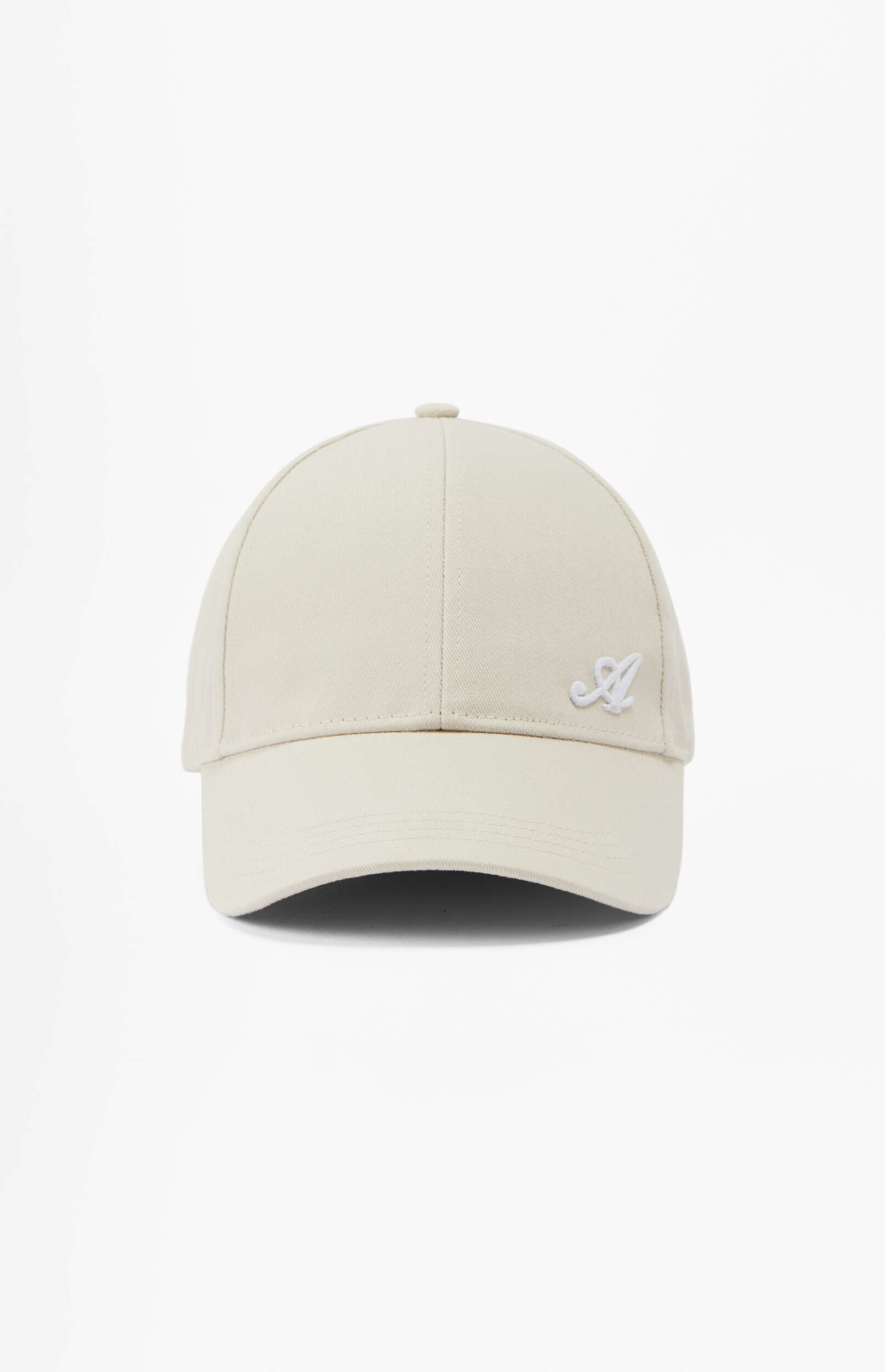 A light beige baseball cap is displayed centered against a plain white background. The cap features a white embroidered cursive letter 'A' on its front left panel.