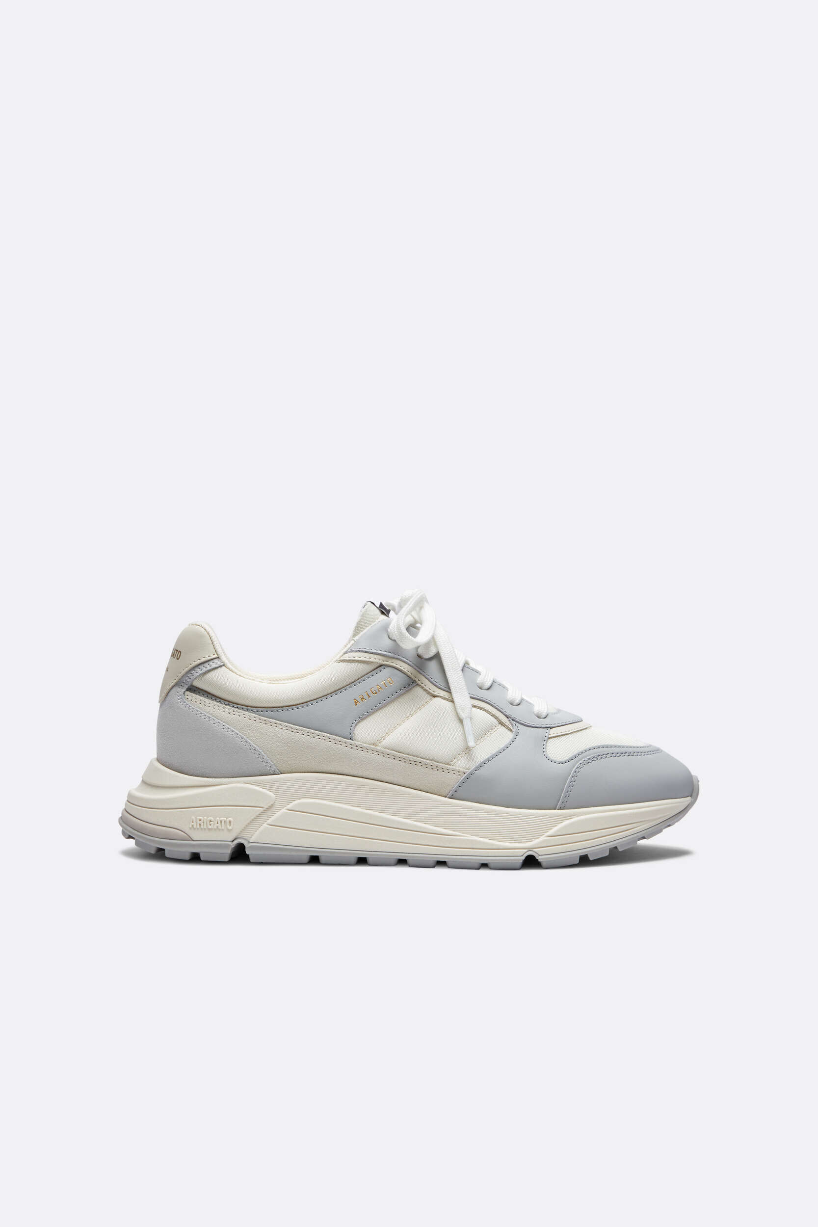 A single Axel Arigato Genesis vintage runner sneaker in light grey and off-white, shown in a side profile on a clean white background. The shoe features a multi-paneled upper, white laces, and a chunky light-colored sole with 'ARIGATO' embossed near the heel.